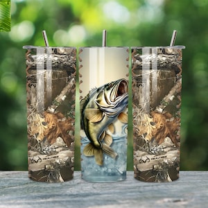 Könnte beinhalten: Drei Edelstahlbecher mit Tarnmuster und einem Bassfisch-Design. Die Becher haben einen braunen lederartigen Riemen um die Mitte. Die Becher stehen auf einer Holzoberfläche.