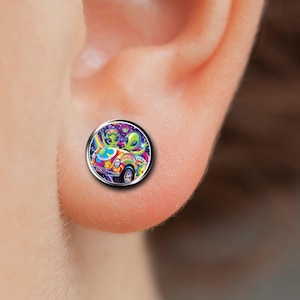 May include: A pair of silver stud earrings with a colorful image of two aliens driving a car in space. The car has a peace sign on the side and the aliens are wearing sunglasses.