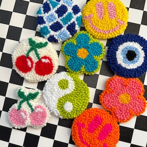 May include: Eight colorful embroidered patches with various designs, including a smiley face, a flower, a cherry, and a yin yang symbol.