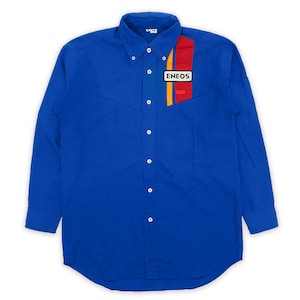 May include: A long-sleeved blue button-down shirt with a red, yellow, and white stripe design on the left chest. The shirt features the "ENEOS" logo in a white rectangle. The shirt has a button-down collar and white buttons.