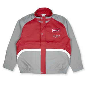 May include: A grey and red jacket featuring the ENEOS logo on the chest. The jacket has a white stripe across the front and a small pocket. It has a button-up front and a collar.