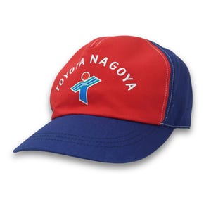 May include: A red and blue baseball cap with the text "TOYOTA NAGOYA" in white. The cap features a logo with a person-shaped figure. The brim and back of the cap are blue, while the front is red.