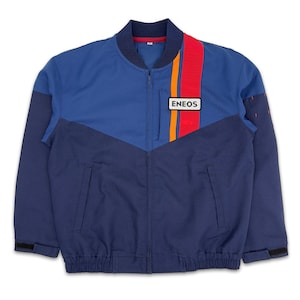 May include: A blue and navy blue bomber jacket with a zip fastening and a patch that says "ENEOS" on the right side. The jacket has a red and orange stripe on the right side.