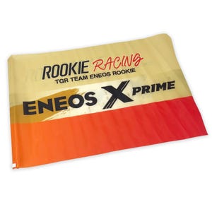 May include: A yellow and orange racing flag with the text "Rookie Racing TGR Team Eneos Rookie Eneos X Prime" printed on it.