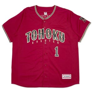 Könnte beinhalten: Ein rotes Baseballtrikot mit schwarzer und goldener Schrift, auf dem "Tohoku Rakuten 1" steht. Das Trikot hat einen Knopfleisten vorne und ein Majestic-Logo unten rechts.