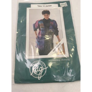 May include: A sewing pattern envelope for a Take 12 Jacket by Merchant & Rag. The packaging is teal with white text and a central photograph showing a jacket with a multi-colored, patterned fabric design, a black turtleneck, and black pants.