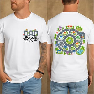 May include: White t-shirt with a colorful graphic on the front that says "DAD" with checkered racing flags. The back of the shirt features a circular road design with houses, trees, and a pond.