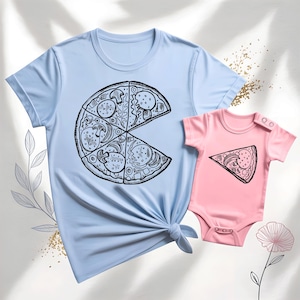 May include: A light blue adult t-shirt and a pink baby onesie. Both garments feature a black and white pizza slice design. The adult shirt has a large pizza slice graphic, while the onesie has a single slice.