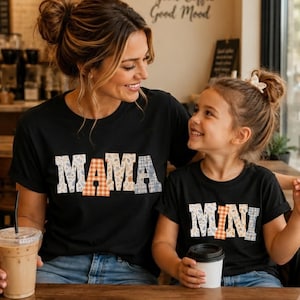 Può includere: Due magliette nere con scritte a blocchi dal design stampato. La maglietta più grande mostra la parola MAMA, mentre quella più piccola mostra la parola MINI. Le lettere presentano un mix di motivi floreali, a quadri e arancione.