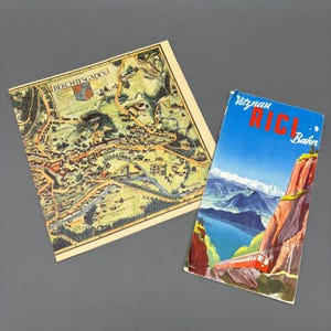 May include: Two vintage travel brochures. One features a detailed map of Berchtesgaden, Germany. The other, titled "Vitznau RIGI Bahn," showcases a scenic mountain landscape with a red train. Both have a cream-colored border.