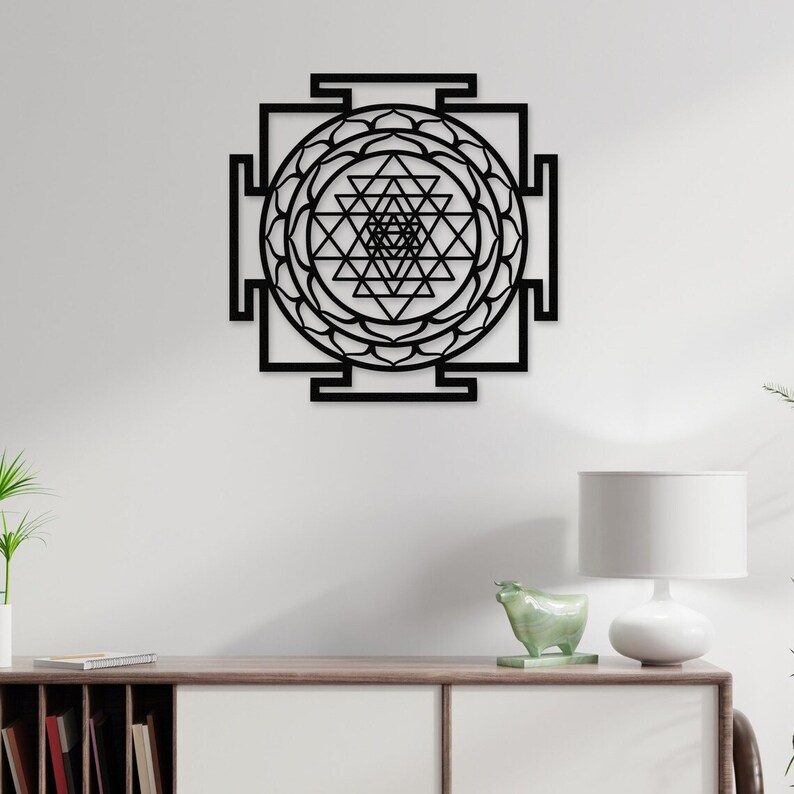 Puede incluir: Arte de pared de metal negro con un dise&ntilde;o geom&eacute;trico conocido como Sri Yantra. El dise&ntilde;o es una disposici&oacute;n compleja de tri&aacute;ngulos y c&iacute;rculos, a menudo asociado con las tradiciones hind&uacute;es y budistas.