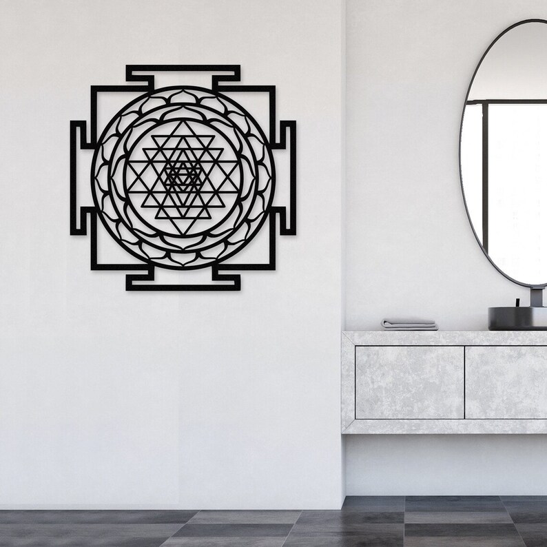 Puede incluir: Arte de pared de metal negro con un dise&ntilde;o geom&eacute;trico y un mandala circular en el centro. El dise&ntilde;o recuerda a un Sri Yantra, un s&iacute;mbolo sagrado en el hinduismo.