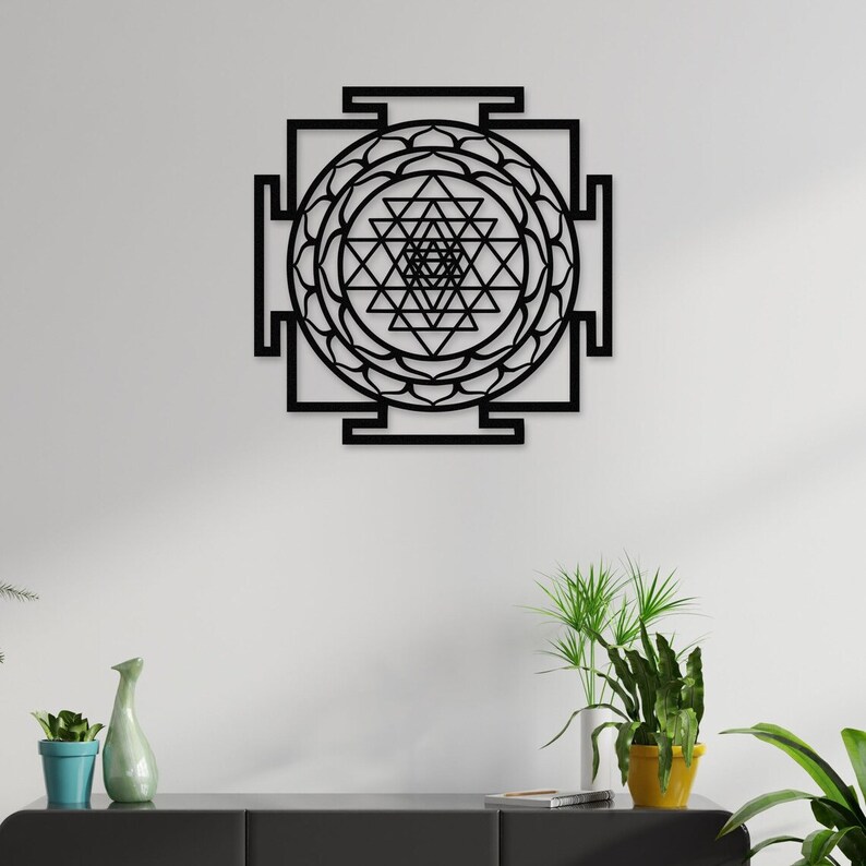 Puede incluir: Arte de pared de metal negro con un dise&ntilde;o geom&eacute;trico y un mandala circular en el centro. El dise&ntilde;o recuerda a un Sri Yantra, un s&iacute;mbolo sagrado en el hinduismo.