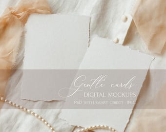 May include: Two white cards with torn edges on a white fabric background with a pearl necklace and a peach coloured ribbon. The text "Gentle cards" and "Digital Mockups" is written on the cards.