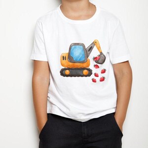 May include: A white t-shirt featuring a cartoon illustration of a yellow excavator digging up strawberries. The excavator has a blue cab and a black arm.