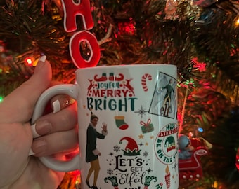 May include: White ceramic mug with a Christmas-themed design featuring Buddy the Elf from the movie Elf. The design includes the text "Joyful Merry Bright", "Let's Get Elfed Up!" and other festive elements.