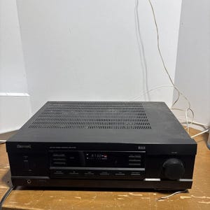 Op de afbeelding: Een zwarte Sherwood AM/FM-stereoreceiver model RX-4103 met een digitaal display dat 97.30 weergeeft. Het apparaat is voorzien van een grote volumeknop aan de rechterkant, meerdere drukknoppen voor ingangsselectie, een aan-uitknop en een hoofdtelefoonaansluiting.