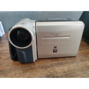 May include: A silver Sharp VL-E630 Viewcam camcorder with a black lens and a red LED light.