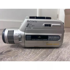 May include: A silver Sony Mich Micro M-100MC micro cassette recorder with a built-in microphone and a clear voice feature. The recorder has a tape counter, a battery indicator, and a mic mode switch.