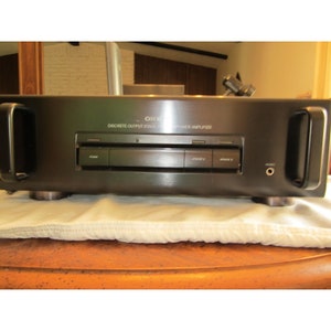Può includere: Un ricevitore stereo Onkyo nero con la scritta "ONKYO DISCRETE OUTPUT STAGE HIGH POWER AMPLIFIER" sul davanti. Il ricevitore ha un pulsante di accensione, pulsanti per gli altoparlanti A e B e una presa per le cuffie.