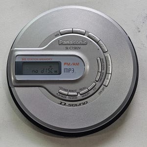 May include: Silver Panasonic SL-CT582V portable CD player. Features FM/AM radio, MP3 playback, and a 30-station memory. The display reads "no disc". Includes buttons for volume, tuning, and mode selection.