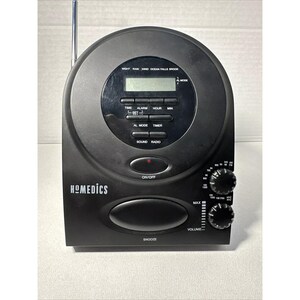 May include: Black clock radio with a digital display and buttons for time, alarm, hour, minute, timer, sound, and radio. The clock radio has a black knob for volume and a black knob for tuning. The clock radio has a black button for snooze and a black button for on/off. The clock radio has the text "HOMEDICS" on the front.