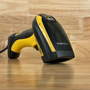 May include: A yellow and black handheld barcode scanner with the text "PowerScan" on the side.