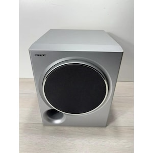 Pu&ograve; includere: Un subwoofer Sony argentato con un grande altoparlante nero.
