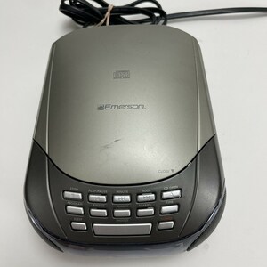 May include: A silver Emerson CD player with a black front panel and a variety of buttons, including stop, play/pause, minute, hour, program, pmode, alarm1, alarm2, sleep, snooze, time, and power. The CD player has a CD open button and a close button.