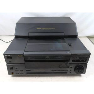 Op de afbeelding: Een zwarte Sony CD-speler met een ingebouwde receiver en een zilveren frontpaneel. De speler heeft een digitaal display en een aantal knoppen om de weergave te bedienen. De speler is gelabeld met "Sony" en "Full Logic" in zilveren letters.