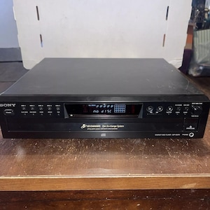 May include: Black Sony CD changer with a digital display that reads "no disc". The CD changer has a silver button that says "CD Changer" and a silver button that says "Disc Ex-change System".