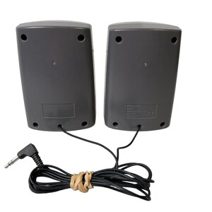 May include: A pair of gray computer speakers with a black audio cable and a 3.5mm jack. The speakers have a black label with text on the back.