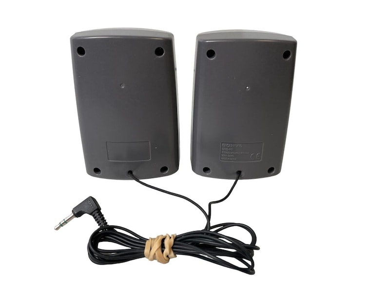 May include: A pair of gray computer speakers with a black audio cable and a 3.5mm jack. The speakers have a black label with text on the back.