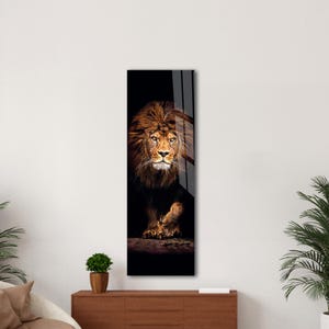 May include: A vertical art piece featuring a majestic lion. The lion has a full, brown mane and is set against a dark background. The artwork is displayed on a wall, adding a touch of wildlife to the decor.