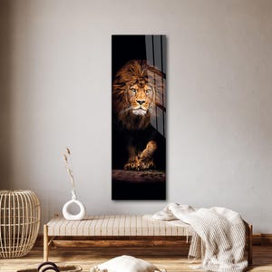 May include: A vertical art print featuring a majestic lion. The lion's golden mane and face are illuminated against a dark background. The artwork captures the lion's intense gaze and powerful presence, creating a striking visual.