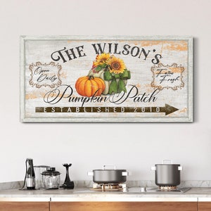 May include: A rustic wooden sign with white paint and a distressed look. The sign reads "The Wilson's Pumpkin Patch Established 2010". It features a pumpkin, sunflowers, and a ribbon. The sign has a brown arrow pointing to the right.