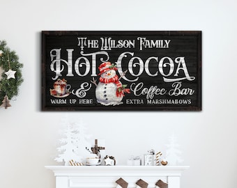 May include: A black chalkboard sign with white text that reads "The Wilson Family Hot Cocoa & Coffee Bar Warm Up Here Extra Marshmallows". A snowman with a red hat and scarf is pictured next to the text.