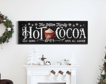 May include: A black and white sign with the text "The Miller Family Hot Cocoa Bar Open All Winter" and a red and white illustration of a mug of hot chocolate with whipped cream and a cinnamon stick. The sign is on a woodgrain background.