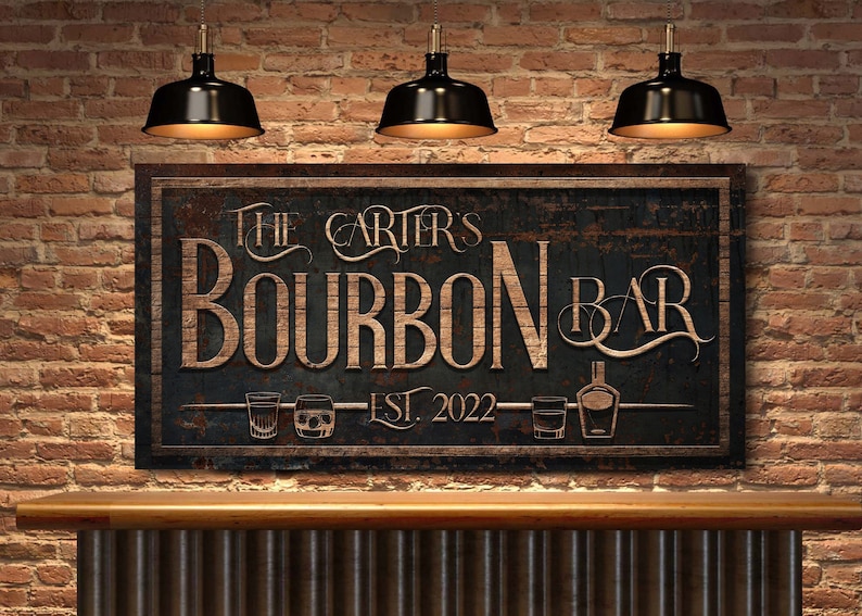 May include: A rustic wooden sign with black paint and a distressed finish. The sign reads "The Carter's Bourbon Bar Est. 2022" with a stylized font and images of glasses and a bottle of bourbon.