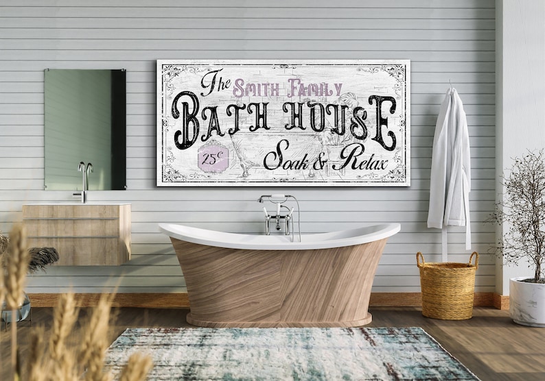 May include: A white wooden sign with black lettering that reads "The Smith Family Bath House 25&cent; Soak & Relax". The sign is hanging on a white shiplap wall above a freestanding bathtub.