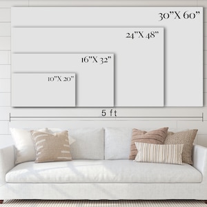 May include: A white sofa with pillows in front of a white wall with four different sizes of blank canvases hanging on the wall. The canvases are labeled with their dimensions in inches. The wall is made of wood planks. The sofa is 5 feet wide.