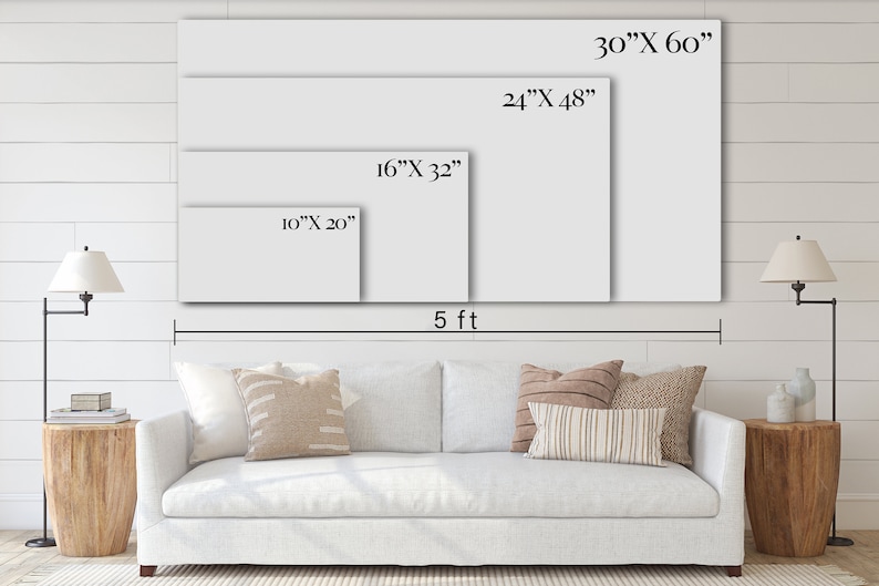 May include: A white sofa with pillows in front of a white wall with four different sizes of blank canvases hanging on the wall. The canvases are labeled with their dimensions in inches. The wall is made of wood planks. The sofa is 5 feet wide.