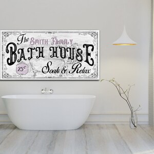 May include: A white sign with black text that reads "The Smith Family Bath House 25&cent; Soak & Relax". The sign is hanging on a white wall above a white bathtub.