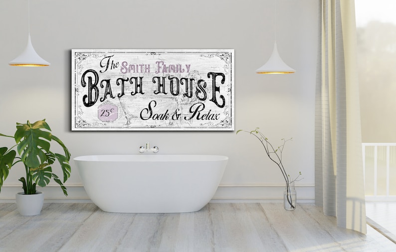 May include: A white sign with black text that reads "The Smith Family Bath House 25&cent; Soak & Relax". The sign is hanging on a white wall above a white bathtub.