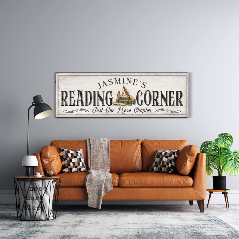 May include: A white wooden sign with black text that reads "Jasmine's Reading Corner Just One More Chapter". The sign has a vintage style and features a stack of books with a bookmark.