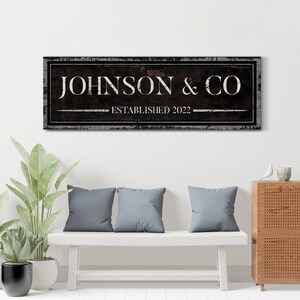 May include: A black and white sign with distressed edges and a rustic woodgrain texture. The sign reads "JOHNSON & CO ESTABLISHED 2022".