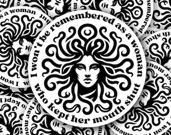 May include: A collection of white stickers with a black illustration of a woman with curly hair. The stickers have the text "I won't be remembered as a woman who kept her mouth shut" in a circular design.