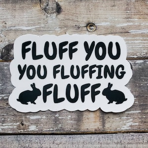 May include: White sticker with black text that reads "Fluff you you fluffing fluff" with two black bunny silhouettes on either side of the text.