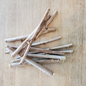 May include: A pile of thin, light brown twigs on a wooden surface.