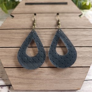 May include: A pair of black teardrop-shaped earrings with a geometric pattern. The earrings have a gold-toned hook closure.